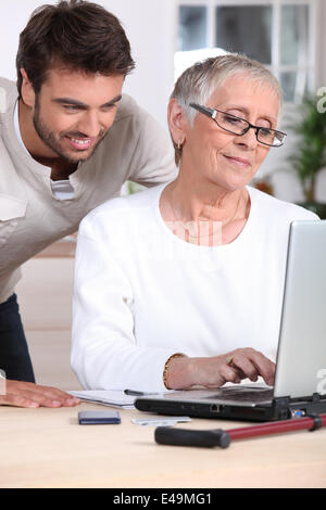 Mann helfen alte Dame mit computer Stockfoto