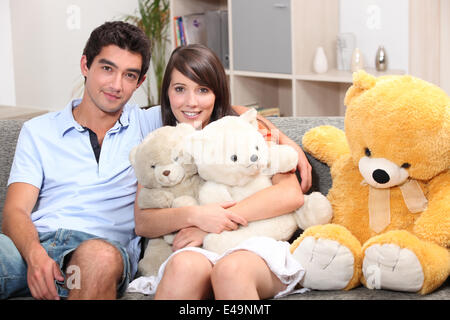 Paar saß auf der Couch mit Kuscheltieren Stockfoto