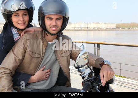 Junges Paar auf einem Moped durch einen Fluss Stockfoto