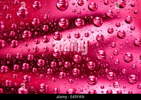 Wassertropfen auf roten Glasoberfläche Stockfoto