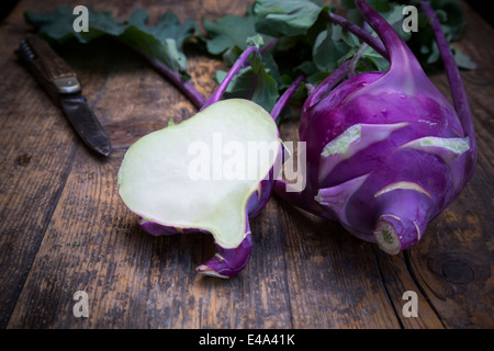 Ganze und eine halbe blaue Rübe Kohl, Brassica Oleracea var. Gongylodes L. und Messer auf dunklem Holz Stockfoto