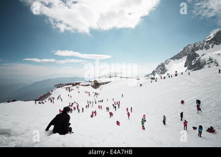 Vor allem einheimische Touristen spielen im Schnee auf Jade Dragon Snow Mountain in der Nähe von Lijiang, Yunnan Provinz, China, Asien Stockfoto