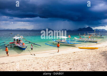 Auslegerboote vor einem Strom Verankerung an einem Sandstrand in der Bacuit Archipel, Palawan, Philippinen, Südostasien Stockfoto