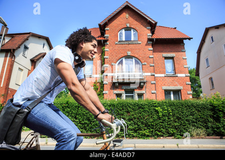 Junge männliche Schüler mit Kopfhörern fahren auf einem Racing-Zyklus Stockfoto