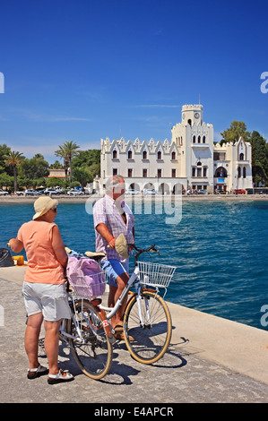 Radfahrer vor einem typischen Gebäude des italienischen Ära ("Residency") Kos-Stadt, Insel Kos, Dodekanes, Griechenland. Stockfoto