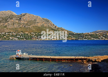 Paar ruht auf einem Dock in Telendos Insel, Dodekanes, Ägäis, Griechenland. Im Hintergrund die Insel Kalymnos. Stockfoto