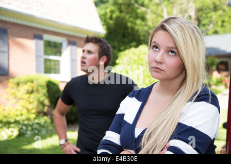 Ein junges Paar mit einer Meinungsverschiedenheit.  Die junge Dame rollt ihre Augen auf den jungen Mann, der scheint abgelenkt und verwirrt in der b Stockfoto