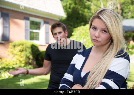 Eine junge Frau starrt in die Kamera, während ihr Freund Gesten wütend in den Hintergrund. Stockfoto