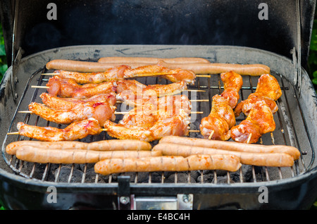 Würstchen und Chicken Wings auf das Rauchen grill barbeque Stockfoto