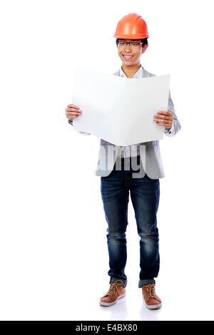 Asiatische junge Mann trägt einen Bauarbeiterhelm Blaupause Papier betrachten Stockfoto