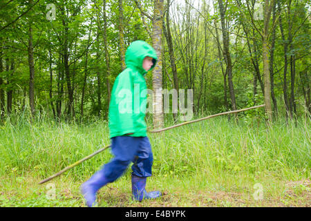 Kleiner Junge im Wald mit einem Stock Stockfoto