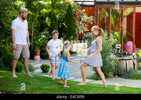 Familie mit zwei Kindern im Garten herumalbern, München, Bayern, Deutschland Stockfoto