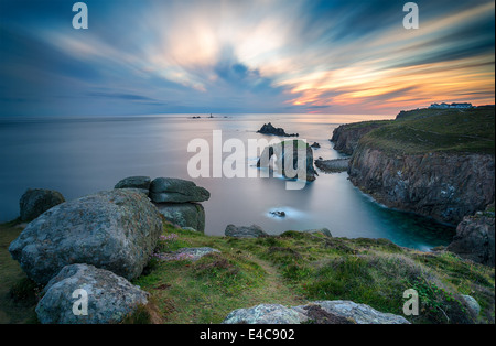 Eine Langzeitbelichtung des Sonnenuntergangs an Lands End in Cornwall in Richtung des langen Schiffe Leuchtturms Stockfoto