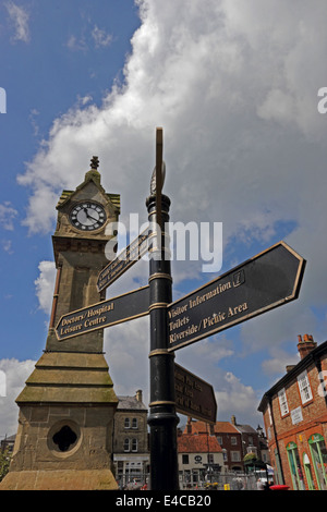 Tourismus-Wegweiser und Clocktower im Marktplatz, Thirsk, North Yorkshire Stockfoto