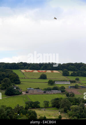 Belper, Derbyshire, UK. 8. Juli 2014.    Ein Weltkrieg zwei Tiger Moth Tipps seine Flügel in Erinnerung, wie er über ein Feld fliegt wo Mohn buchstabieren WW1 in riesigen roten Lettern mit Blick auf Belper in Derbyshire. Die riesigen 100 Fuß Buchstaben wurden von Mitgliedern der Belpers Armee-jüngstere Söhne mit 25 Millionen Mohn im Herbst letzten Jahres - eine für jeden Mann und Pferd getötet in den ersten Weltkrieg gesät. Stockfoto