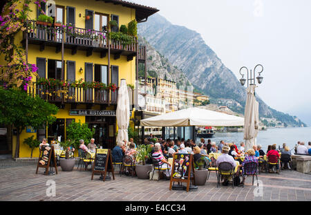 Urlauber, Essen im Freien vor einem Restaurant in der malerischen Ortschaft Limone am Ufer des Gardasee, Italien. Stockfoto