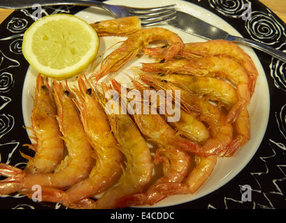 Eine Schüssel mit sautierten Scampi. Ganze Shell auf Garnelen gedünstet in Butter, Knoblauch und Weißwein und mit einer halben Zitrone serviert. Stockfoto