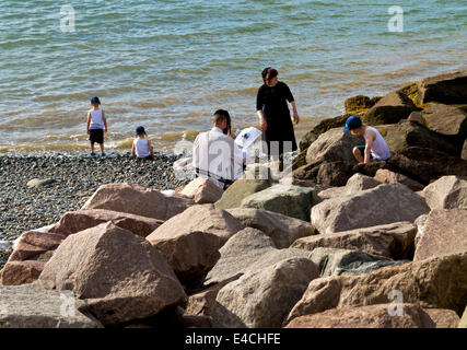 Jüdisch-orthodoxen Familie auf einen Urlaub am Meer bei Penmaenmawr auf der Küste von Nordwales wo die jüdische Gemeinde jährlich besuchen Stockfoto