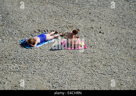 Cornwall. Roseland Halbinsel. St. Mawes Strand. Zwei Frauen auf dem Strand ein SMS und ein Sonnenbad. Stockfoto