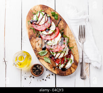 Caprese Salat Tomate und Mozzarella-Scheiben mit Basilikumblättern auf Oliven Holz Schneidebrett Stockfoto