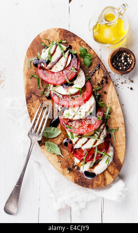 Caprese Salat Tomate und Mozzarella-Scheiben mit Basilikumblättern auf Oliven Holz Schneidebrett Stockfoto