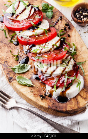 Caprese Salat Tomate und Mozzarella-Scheiben mit Basilikumblättern auf Oliven Holz Schneidebrett Stockfoto