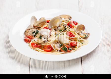 Pasta mit Meeresfrüchten mit Muscheln in Tomatensauce Spaghetti Alle Vongole auf weißem Holz Hintergrund Stockfoto