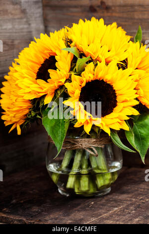 Schöne frische Sonnenblumen in Vase auf hölzernen Hintergrund Stockfoto