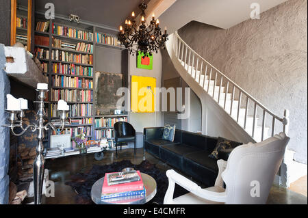 Wohnzimmer in einem restaurierten Schloss mit integrierten Book Regale, schwarzes Leder Corbusier Sofa, weiße Fauteil Sessel und Chrom c Stockfoto