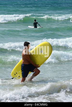 Surfer aus dem Meer mit Surfbrett Stockfoto