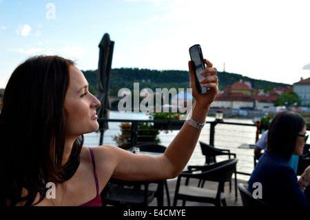 Eine junge Dame auf einem Boot, wobei ein Selbstporträt mit einer Brücke, den Fluss und einer Stadt im Hintergrund. Stockfoto