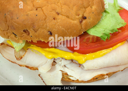 Ganz in der Nähe Blick auf ein Truthahn-Sandwich auf einer Zwiebel Rollen mit Salat, Tomaten und Senf. Stockfoto