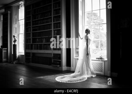Hochzeitsvorbereitungen, Braut im Hochzeitskleid von Fenster, Dorset, England