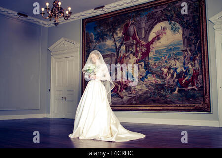 Braut steht im Brautkleid gegen alte Gemälde, Dorset, England Stockfoto