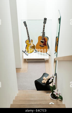 Zwei Gitarren auf Treppe Landung mit schwarzen Verner Panton S Stuhl Stockfoto