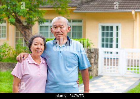 asiatische senior Brautpaar stehend vor einem Haus Stockfoto
