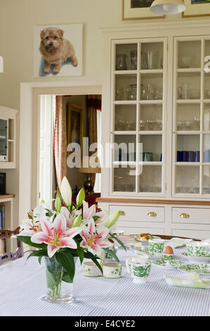 Eine Vase mit Stargazer Lilien schmücken ein Frühstück gedeckten Tisch mit Dragon grün Geschirr von Coalport. Stockfoto