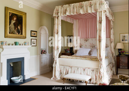 Schlafzimmereinrichtungen Bett mit Chintz Vorhänge in Olivgrün Schlafzimmer mit Kamin. Malen nach Farrow and Ball Stockfoto