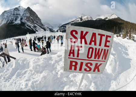 Skate auf eigenes Risiko, Schild am Lake Louise, mit Dutzenden von Skatern in Ansicht, Banff Nationalpark, Alberta Stockfoto