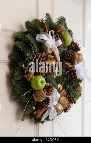 Weihnachtskranz an Eingangstür mit Tannenzapfen und Äpfeln, entworfen von Floristen Hayford & Rhodos Stockfoto