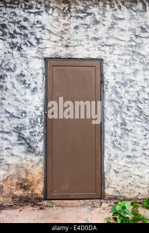 Grobe Betonwand mit Holztür. Stockfoto