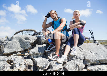 Passen Sie Radfahrer-paar eine Pause auf felsigen Gipfel Stockfoto