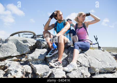 Passen Sie Radfahrer-paar eine Pause auf felsigen Gipfel Stockfoto