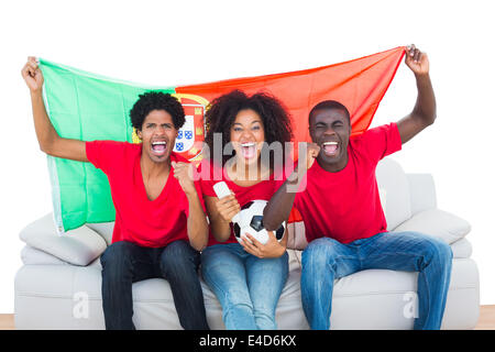 Jubelnde Fußballfans im roten sitzen auf der Couch mit Portugal Flagge Stockfoto