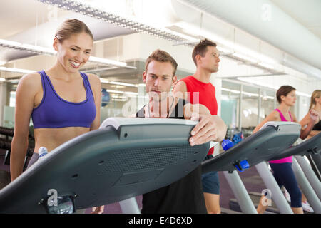 Trainer im Gespräch mit seinem Mandanten auf dem Laufband Stockfoto