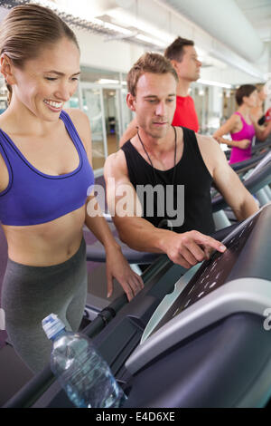 Trainer im Gespräch mit seinem Mandanten auf dem Laufband Stockfoto