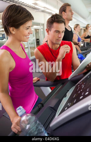 Trainer im Gespräch mit seinem Mandanten auf dem Laufband Stockfoto