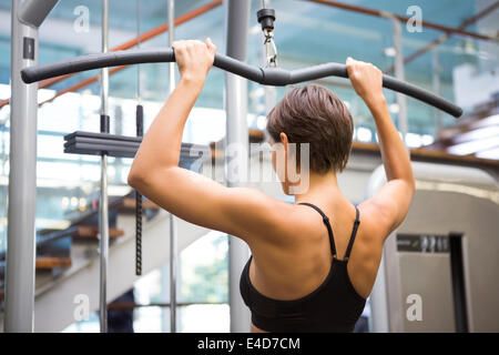 Fit Brünette mit Gewichte Maschine für Arme Stockfoto