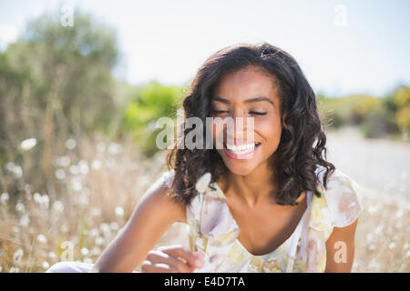 Gerne hübsche Frau sitzen auf dem Rasen in geblümten Kleid Stockfoto