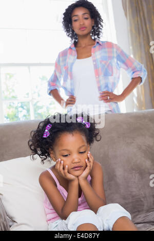 Hübsche Mutter wacht über ihre gereizte Tochter auf dem sofa Stockfoto